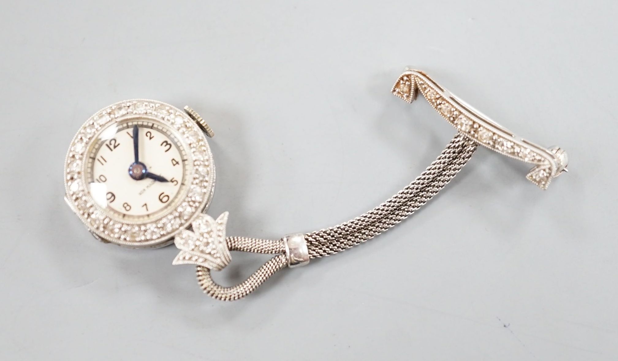 A lady's 1920's white metal (stamped platinum) and diamond chip set lapel watch, 6cm, gross weight 10.7 grams.